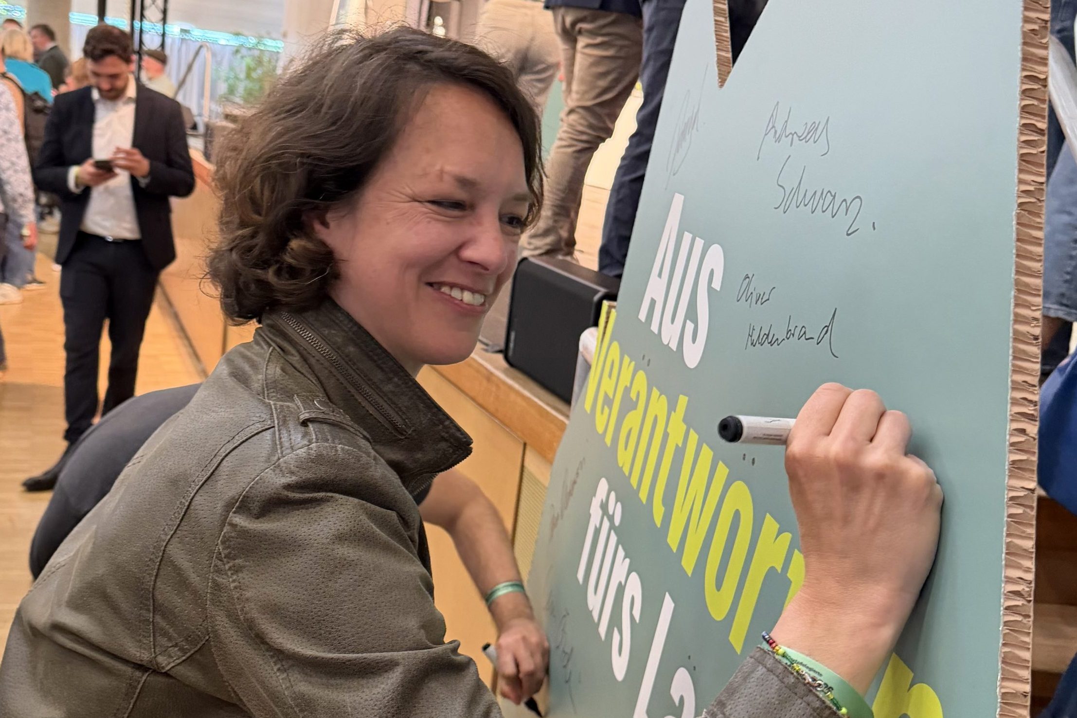 Mariska unterschreibt auf einem Aufsteller in Baden-Württemberg-Form.